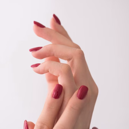 closeup-hands-young-woman-with-long-red-manicure-nails-against-white-background_530697-5779